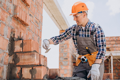 Homem construindo parede de tijolos. Construção tradicional em reforma zinz