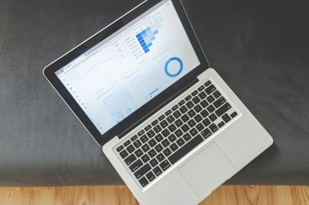 Tela de notebook aberta com gráficos e indicadores de planejamento, sobre sofá