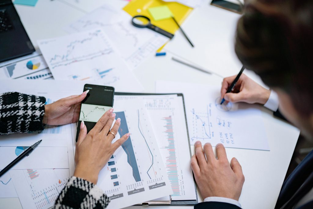 Duas pessoas analisando gráficos e indicadores financeiros sobre uma mesa com documentos de planejamento estratégico