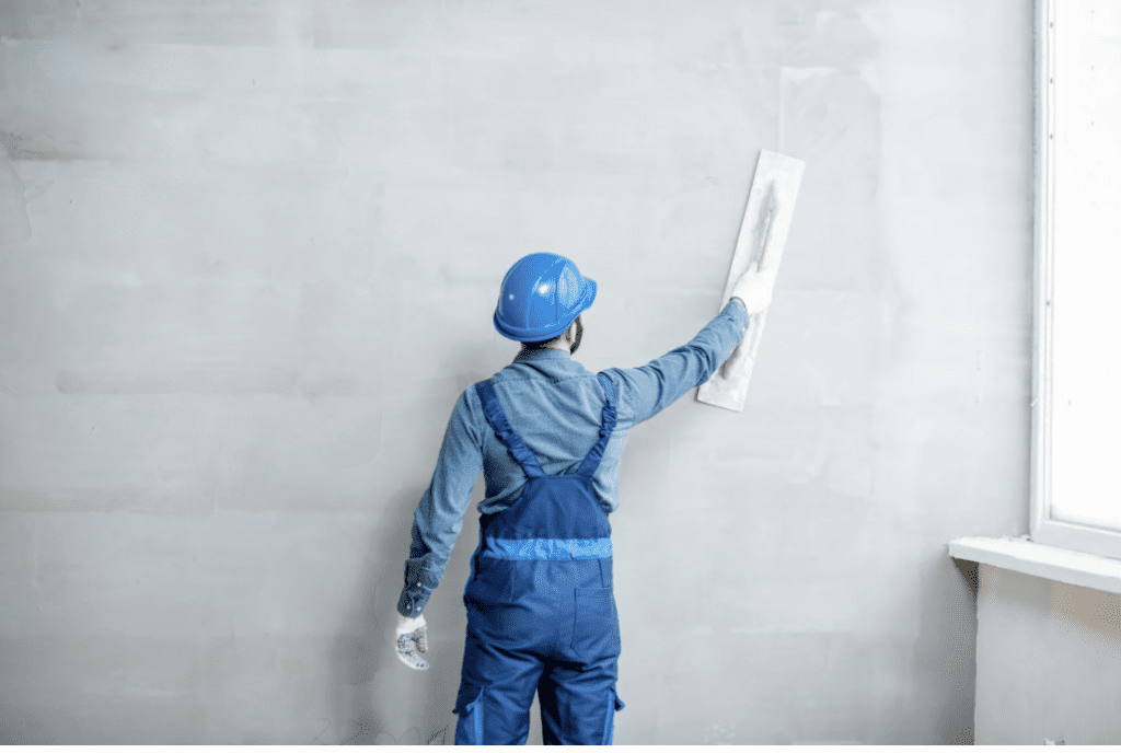 Trabalhador organizando placas de drywall em estrutura metálica de obra comercial.