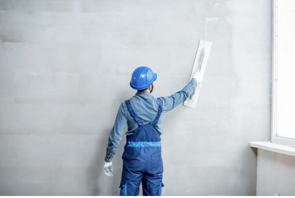 Trabalhador organizando placas de drywall em estrutura metálica de obra comercial.